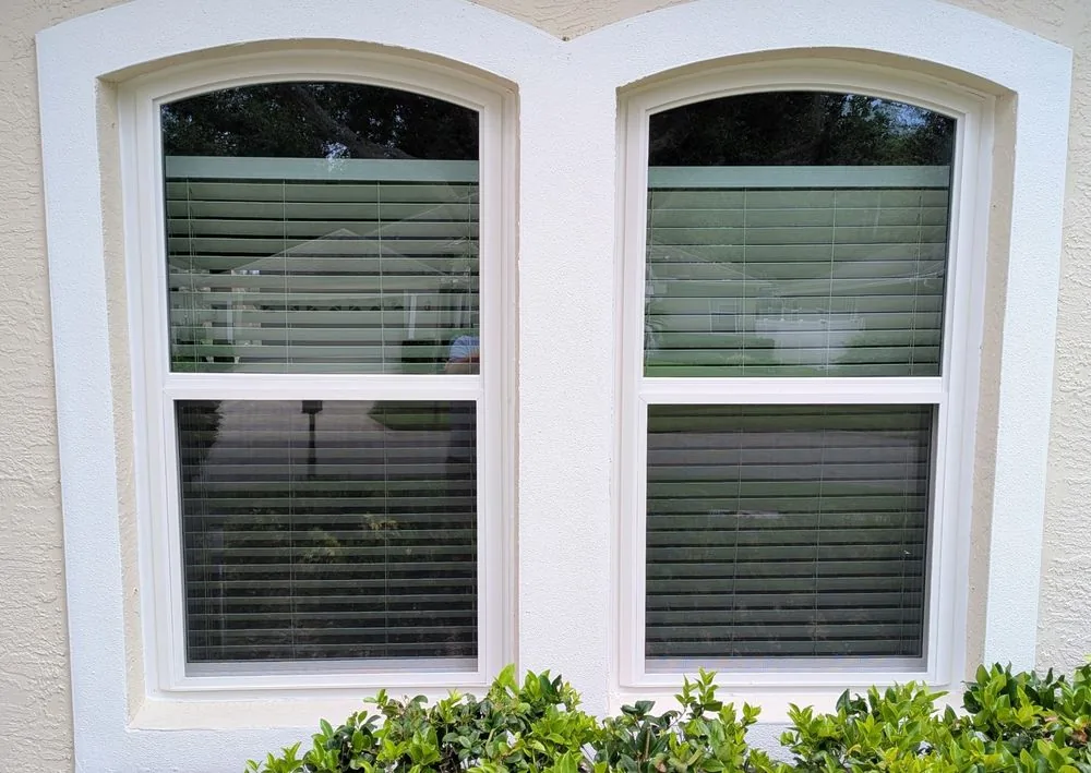 A pair of white arched-top single hung windows in a Central Florida stucco home, installed without grids.