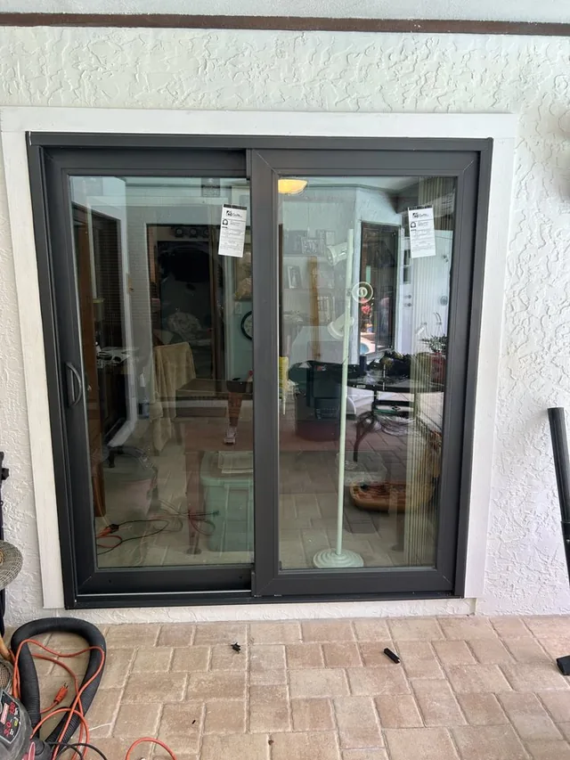 Dark-framed two-panel sliding glass door viewed from a paver patio.