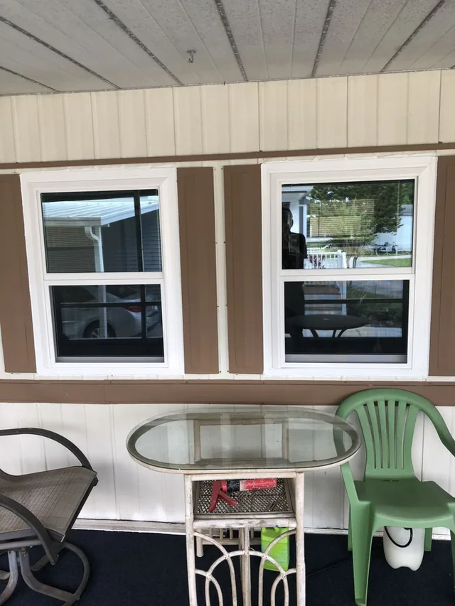 Two white-framed windows above a table on a covered porch.