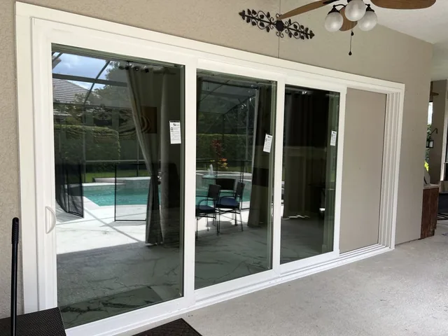 Wide white-framed sliding glass door beside a screened pool patio.