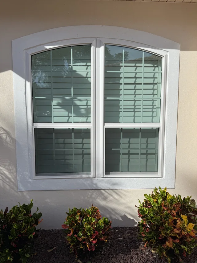 The replacement white-framed arched window with decorative grids, installed by Colonial.