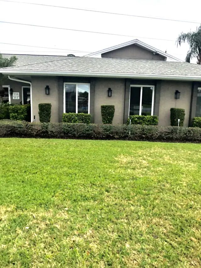 White-framed windows across a gray home exterior above garden hedges.
