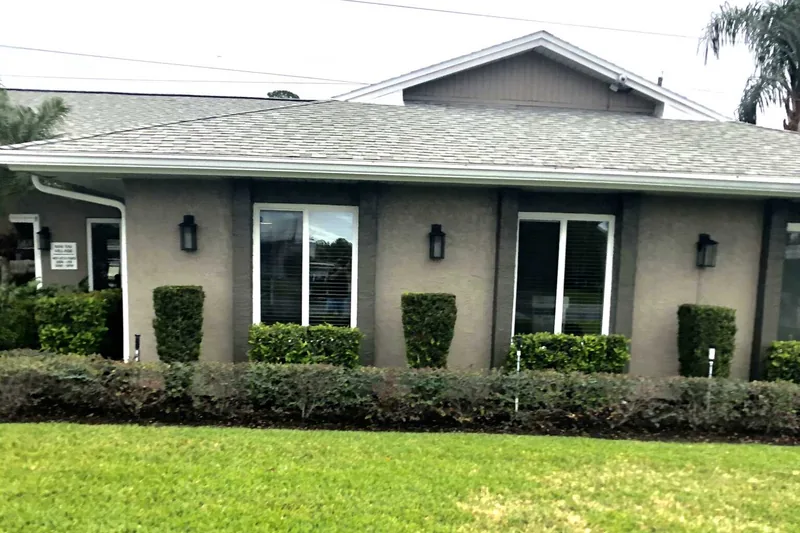 White-framed windows across a Colonial project home with a gray exterior and garden hedges